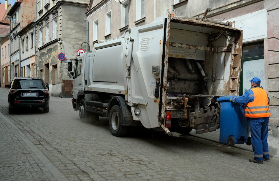 A large pile of mixed plastic waste and household rubbish is spread across an outdoor area, with various containers, including bottles, tubs, and packaging materials in multiple colors such as white, 
